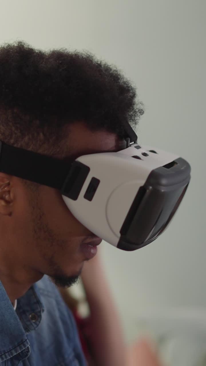Black man with VR goggles and young woman enjoy sports competition in apartment slow motion. Technology of augmented reality to have fun