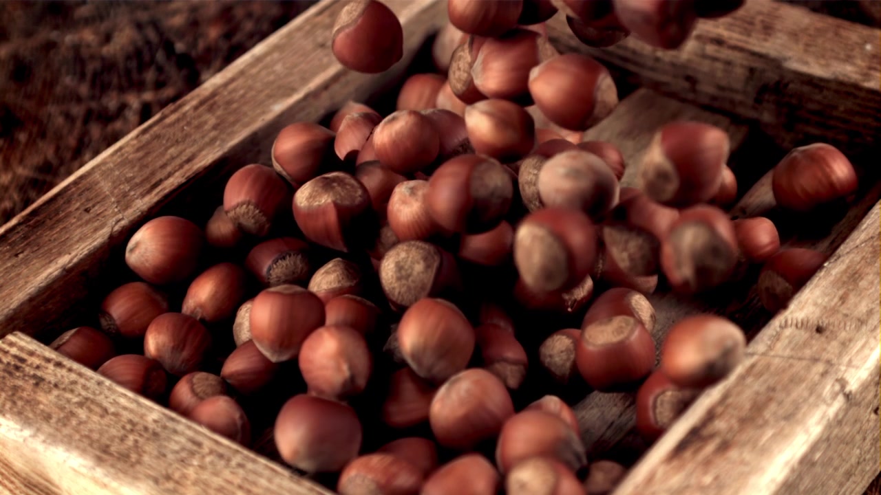 Nocciole che cadono in una scatola di legno rustica al rallentatore