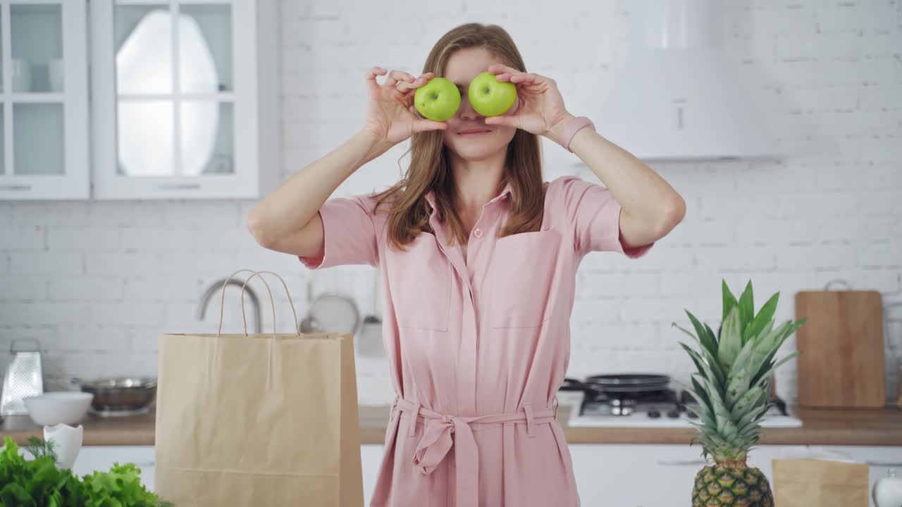 Woman in modern kitchen. Adorable girl having fun with apple in modern light white kitchen