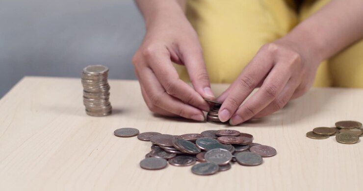 Una persona organizza monete su un tavolo, evidenziando l'importanza della gestione del budget e della consapevolezza finanziaria.