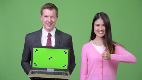 young asian woman and young businessman showing laptop together