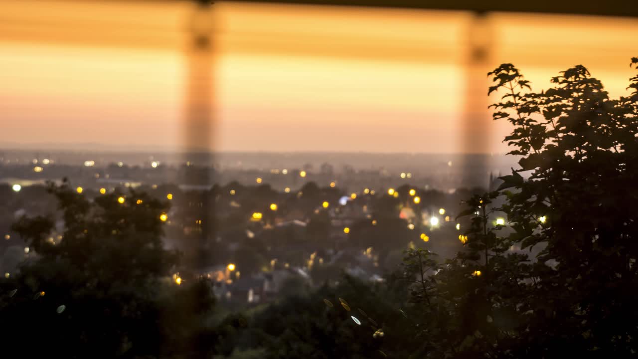 BIg orange sunset over manchester blurred back ground , shot through a window with a tree in focus