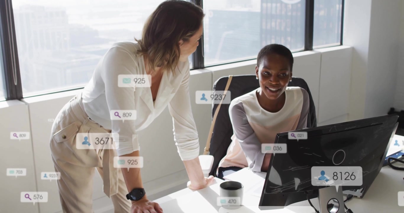 Two colleagues pointing at monitor and clicking keyboard monitoring rising marketing data overlays