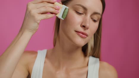 mujer usando un rodillo de jade para el masaje facial