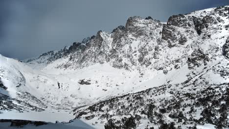 Establishing-overview-of-epic-exposed-rocky-mountain-ledges-covered-in-a-fresh-dusting-of-white-snow