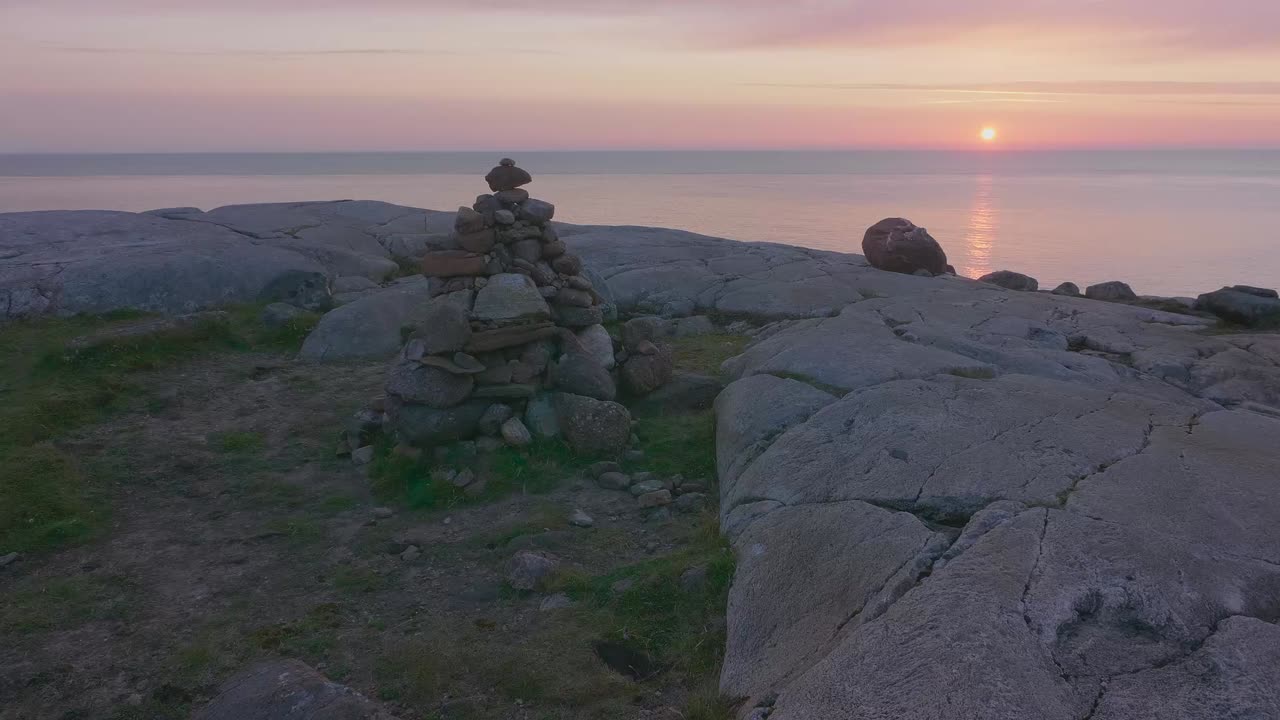 Static sunset shot at Sheigra, Scotland. Cairn in the foreground with the glowing Atlantic horizon and rugged coastal rocks at dusk