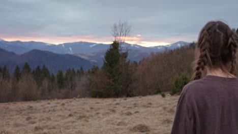 woman in nature with mountains at sunset