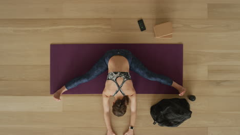 overhead view flexible yoga woman practicing wide-angle seated forward bend pose enjoying healthy lifestyle exercising in fitness studio training on exercise mat