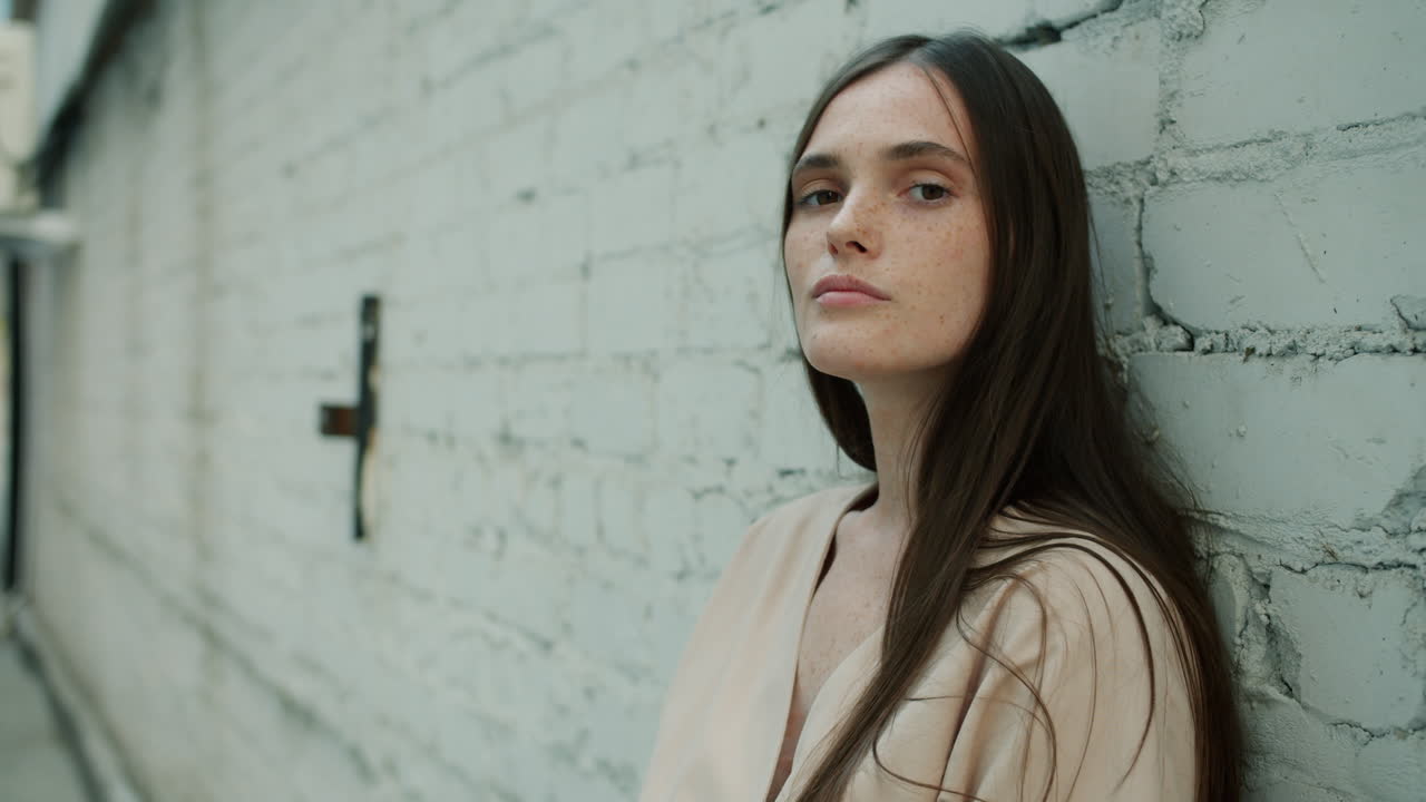 Woman leaning against a brick wall