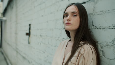 woman leaning against a brick wall