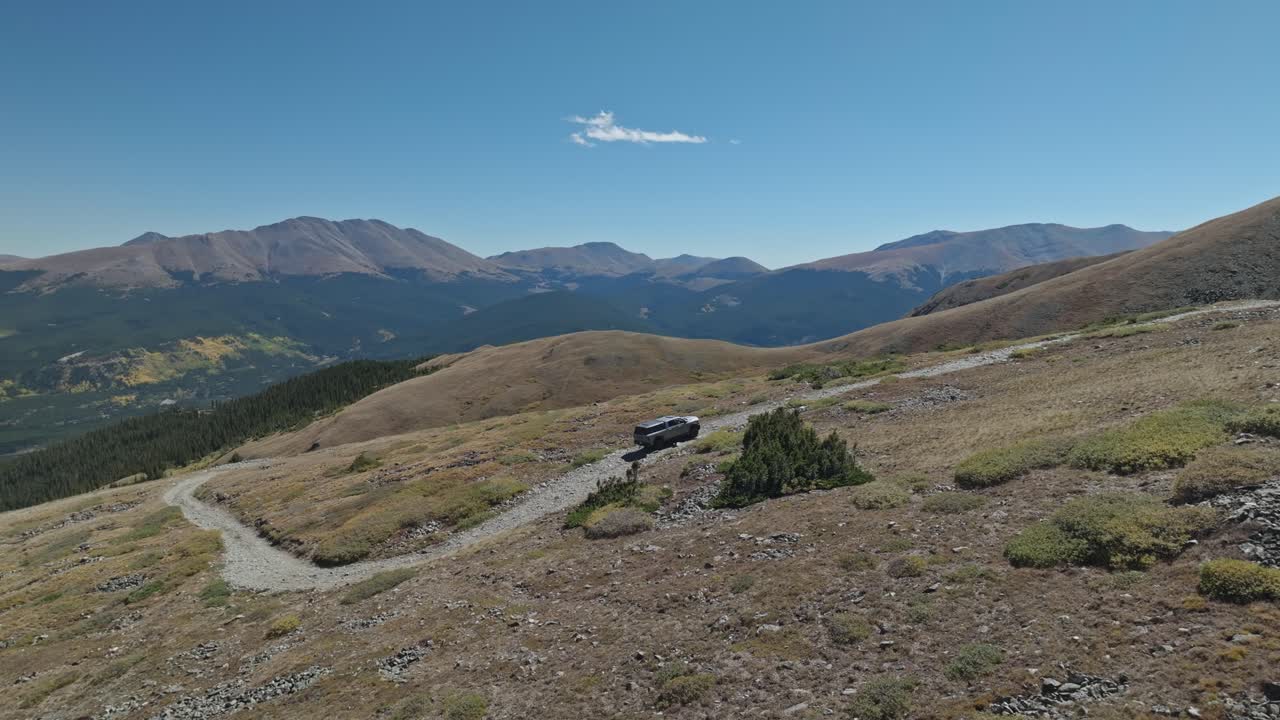 Aerial trucking pan follows truck rising along dirt road of Peak 10 trail Breckenridge Colorado