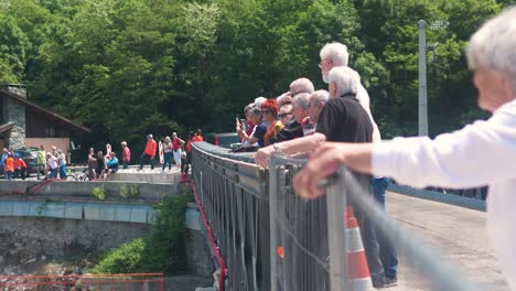 people gather on a bridge watching construction rigging in tende, france on a sunny day
