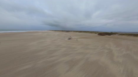 Seagull-passing-a-drone-flying-towards-a-wooden-ship-on-the-beach