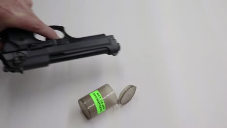 persona colocando una botella vacía de pastillas para dormir y luego recogiendo un arma de fuego