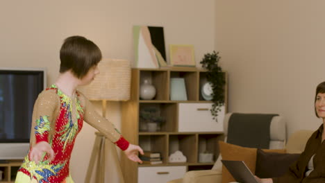 Happy-teenager-with-down-syndrome-dancing-and-jumping-in-the-living-room-and-her-mother-is-looking-at-her