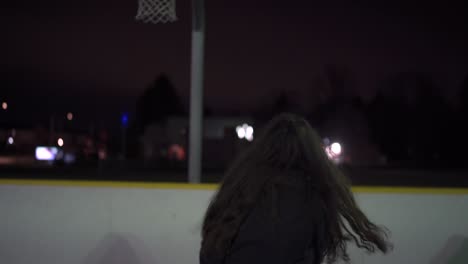 Una-Chica-Con-Cabello-Castaño-Corre-Y-Dispara-A-La-Red-En-Una-Cancha-De-Baloncesto-Al-Aire-Libre-Con-Luces-Por-La-Noche