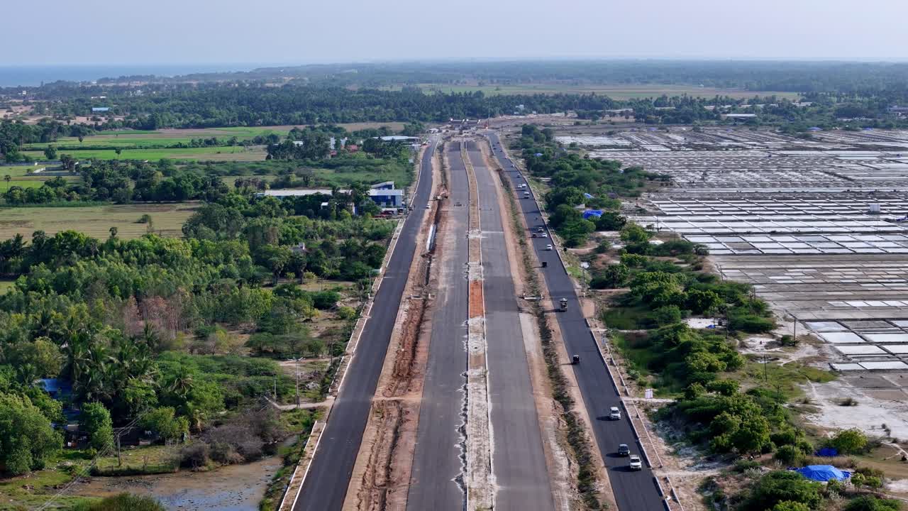 A cinematic drone footage contrasts the organized patterns of a salt pan with the flowing lines of a modern highway. A compelling visual of the intersection of industrial work and human development