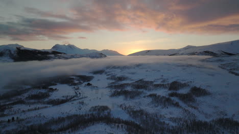 vibrant sunset over white snowy winter landscape with low clouds, arctic