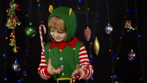 kid girl in christmas elf santa helper costume dancing, fooling around. new year holiday celebration