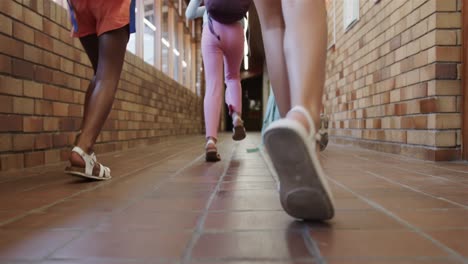 Diverse-schoolgirls-with-school-bags-running-at-elementary-school-corridor-in-slow-motion