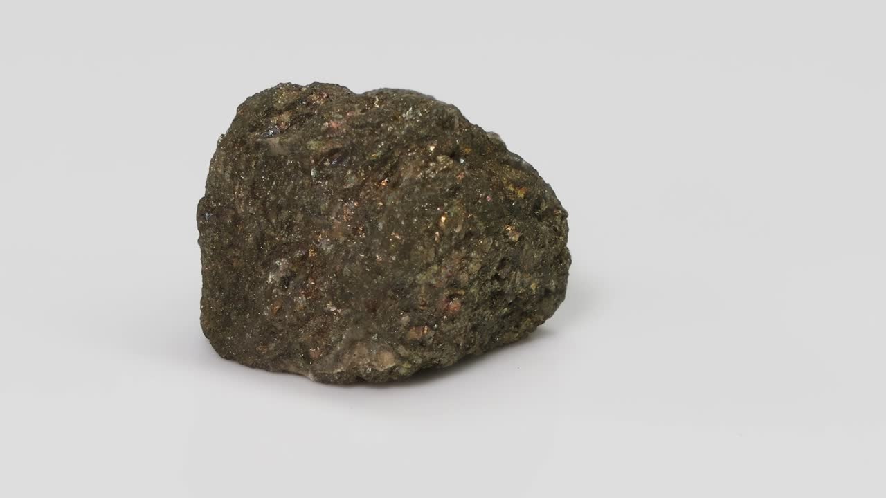 A detailed view of a dark, rough-textured mineral specimen on a neutral background.