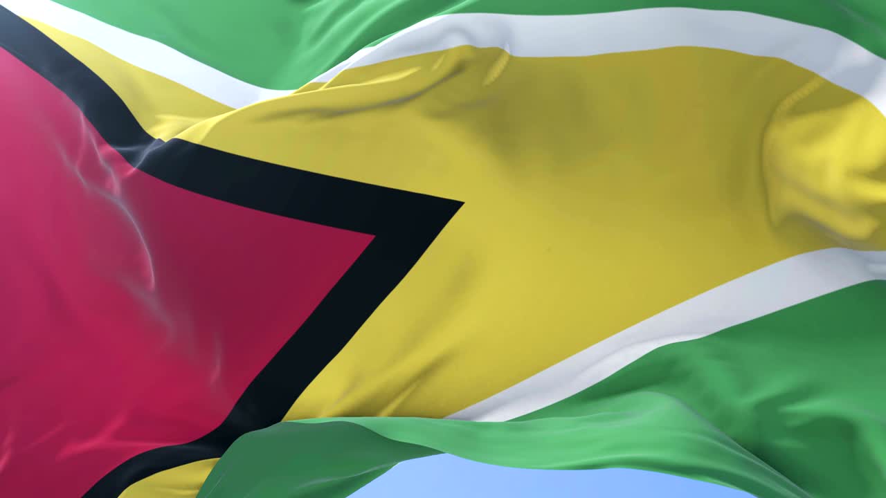 Guyana flag waving at wind in slow in blue sky, loop