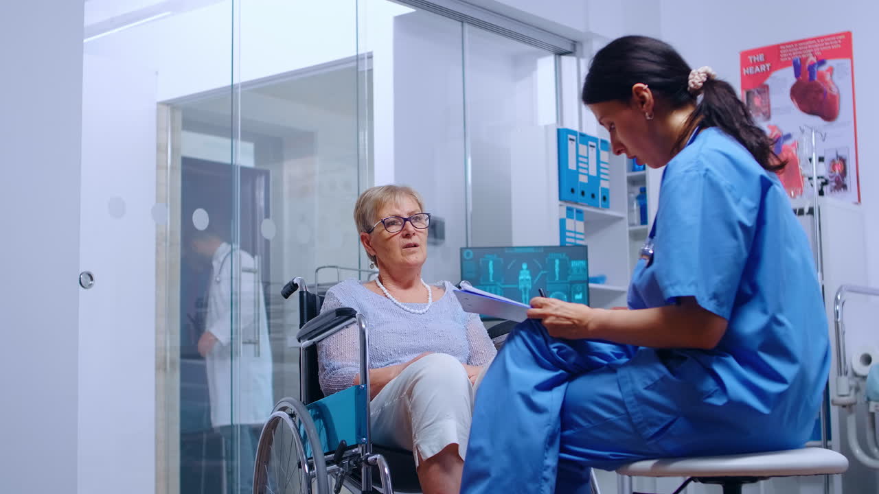Handicapped senior woman in wheelchair talking with nurse