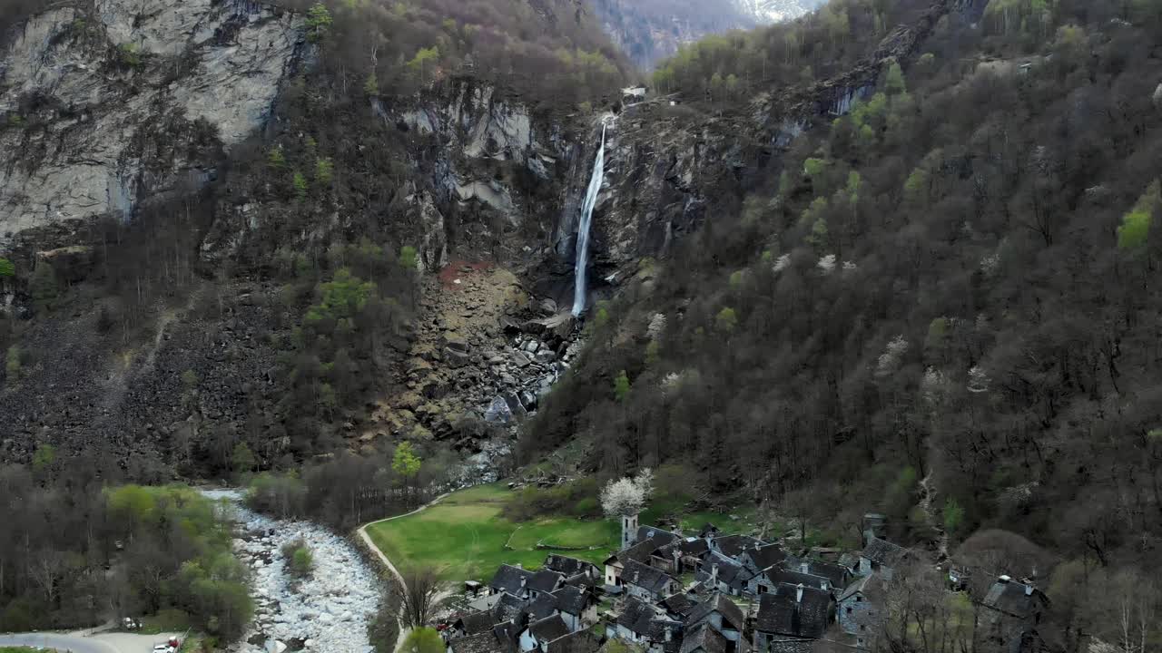 sobrevuelo aéreo sobre los tejados de las antiguas casas de piedra del pueblo de foroglio en ticino, suiza hacia la cascada al atardecer