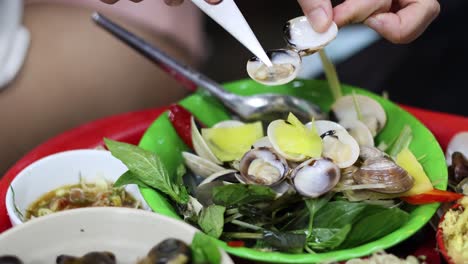 hands peeling shellfish on a vibrant seafood dish