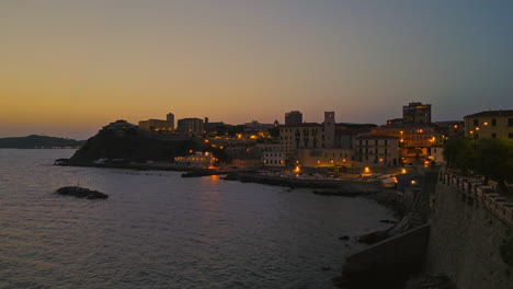 Tuscan-beach-coastline-homes-lit-by-red-street-light-glow-at-sunset,-italy