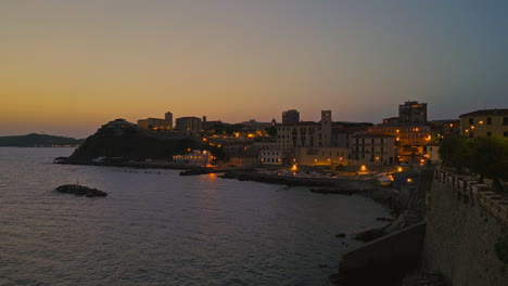 tuscan beach coastline homes lit by red street light glow at sunset, italy
