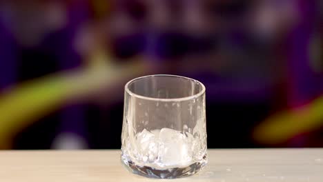 an ice cube dramatically falls into a glass, creating splashes, captured in slow motion with vibrant background colors