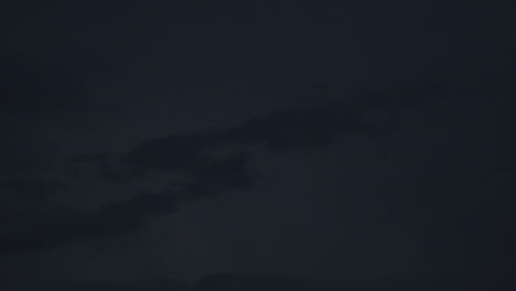 gentle lightning illuminates dark clouds in the night sky, creating drama