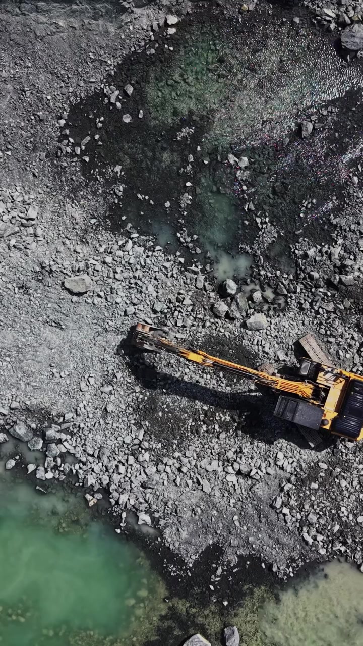 Granite quarry and blue lake in green landscape aerial