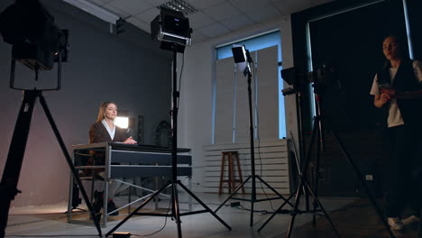 caucasian woman checking a camera directed on the lady sitting at desk. backstage of the footage in modern studio. low angle view