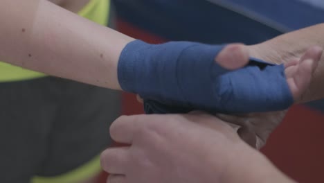 boxer trainer wrapping hands before fighting in slow motion. close-up of young athlete getting ready for fight. man preparing.