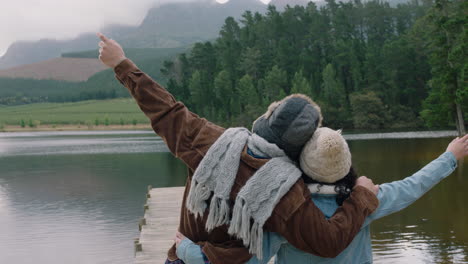 happy couple hugging looking at beautiful lake celebrating with arms raised lovers hug feeling happy on cold winter day