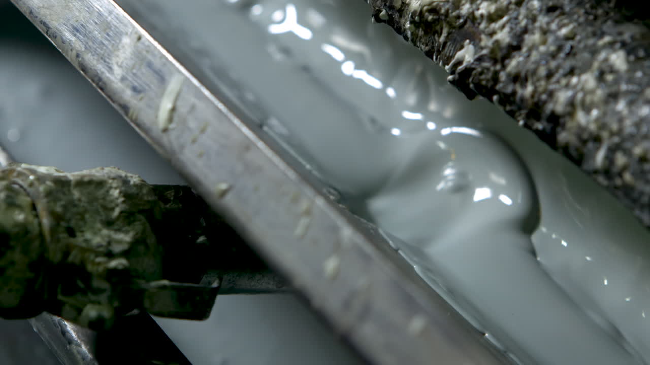 Panning extreme closeup of bubbling light green-grey paint in an old and grungy wallpaper printer