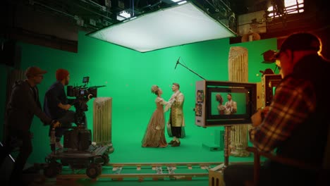 on film studio set clapperboard shuts and director says "action", cameraman starts shooting green screen scene with two talented actors wearing renaissance clothes talking. history costume drama movie