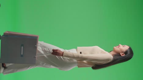 side view of an asian shopping woman with shopping bags smile and walking in front of green screen