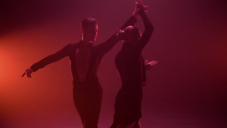 graceful man woman dancing indoors. sexy couple performing paso doble on stage.