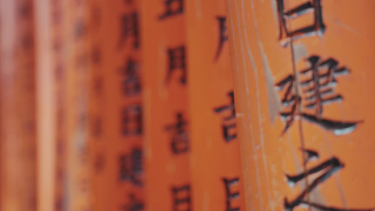 Close-up of vibrant orange torii gates of Fushimi Inari Shrine in Kyoto, adorned with elegant Japanese calligraphy, creating a mesmerizing spiritual passage rich in history and tradition.