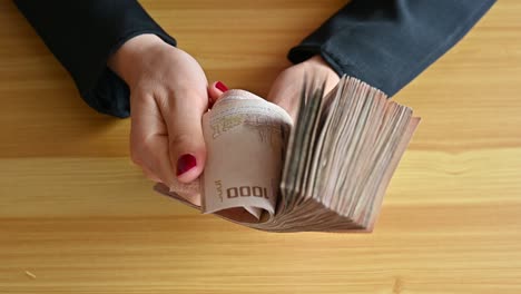 high angle view of an accountant woman holding one thousand thai baht banknotes.