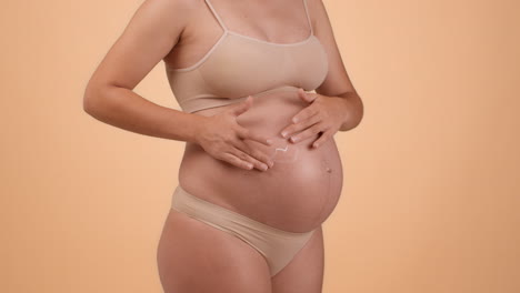 pregnant woman applying lotion to belly