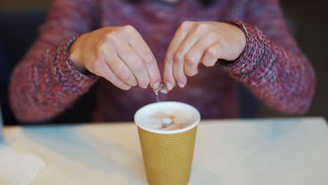girl adding sugar to her coffee in a fast food restaurant. coffee break in cafe