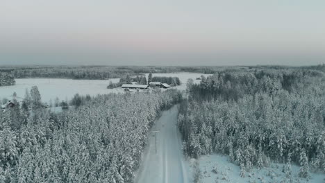 空中,無人機拍攝,在雪地道路上,在冬天的樹木之間,向農場,在卡雷利亞鄉村,在陽光明<unk>的冬天晚上,在vuoniemi,在北卡雷利亞,芬蘭