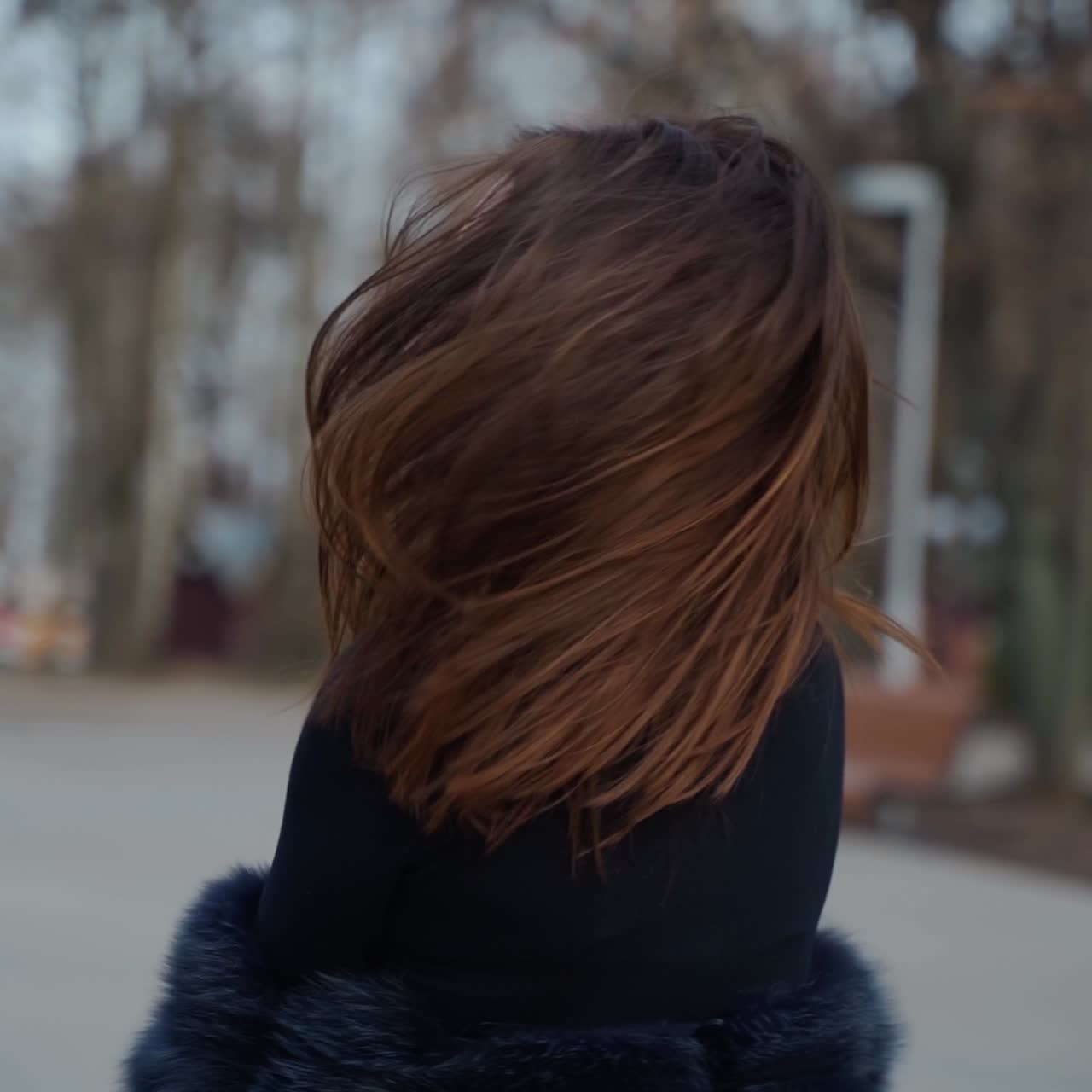 Dark-haired girl spinning around in the park. Attractive young woman in black glamour clothing posing on camera outdoors.