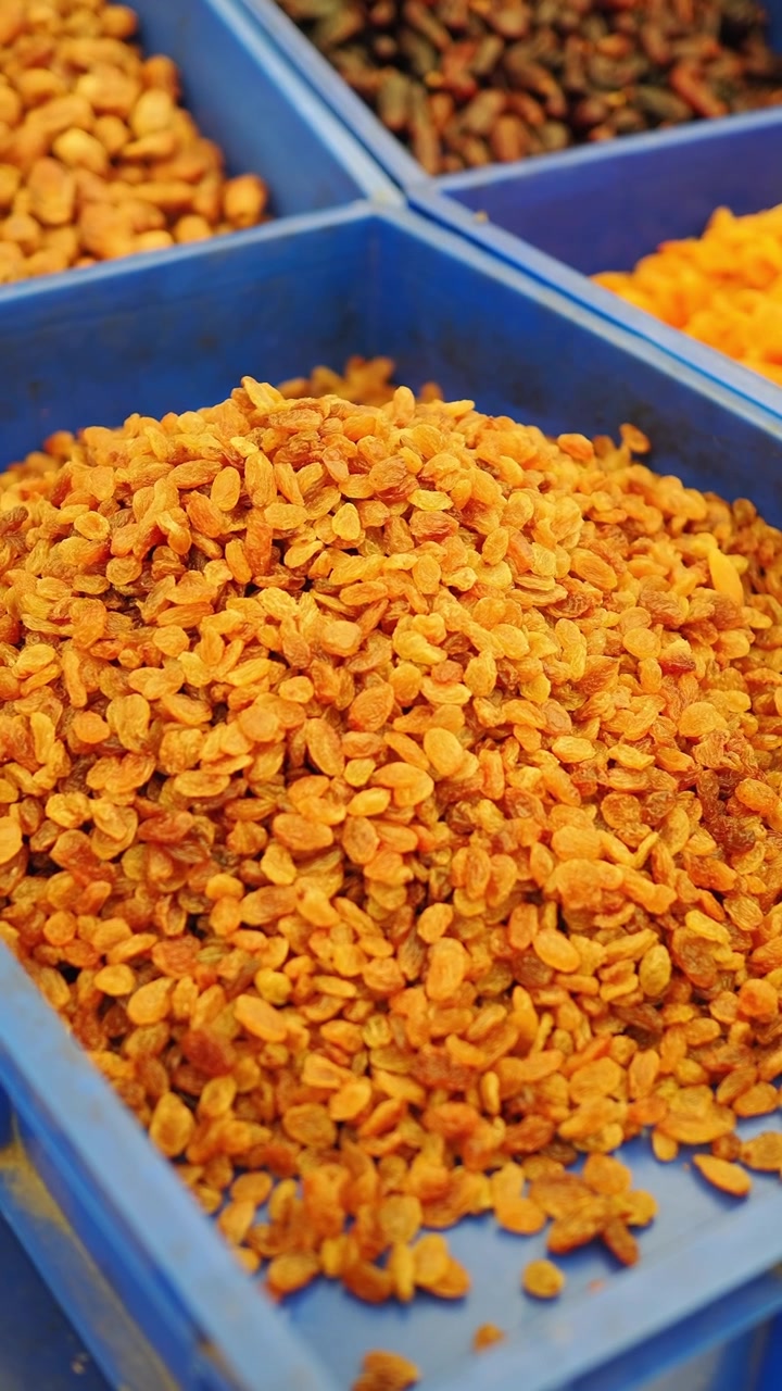 Pile of Golden Raisins in a Blue Plastic Bin