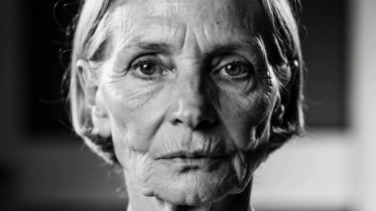 Registrazione: donna anziana che mantiene lo sguardo, mostrando piccoli movimenti mentre la telecamera zooma, con fotogrammi sfocati.