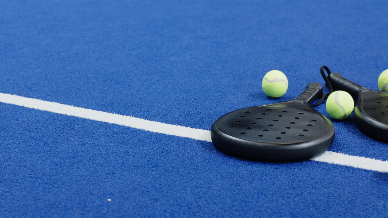 Padelbat og bolde på blå bane, klar til spændende kamp, med plads til tekst.